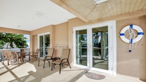 A covered outdoor area with a table and chairs, a glass door, and a life preserver on the wall. - RARE Waterfront Western Exposure Vacation Home - Best Sunset Views & FREE WiFi (Marco Island)