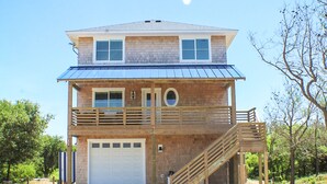 A two-story house with a garage, a balcony, and a staircase leading to the upper floor. - 4X4 beach. Private Pool opens in May (Corolla)