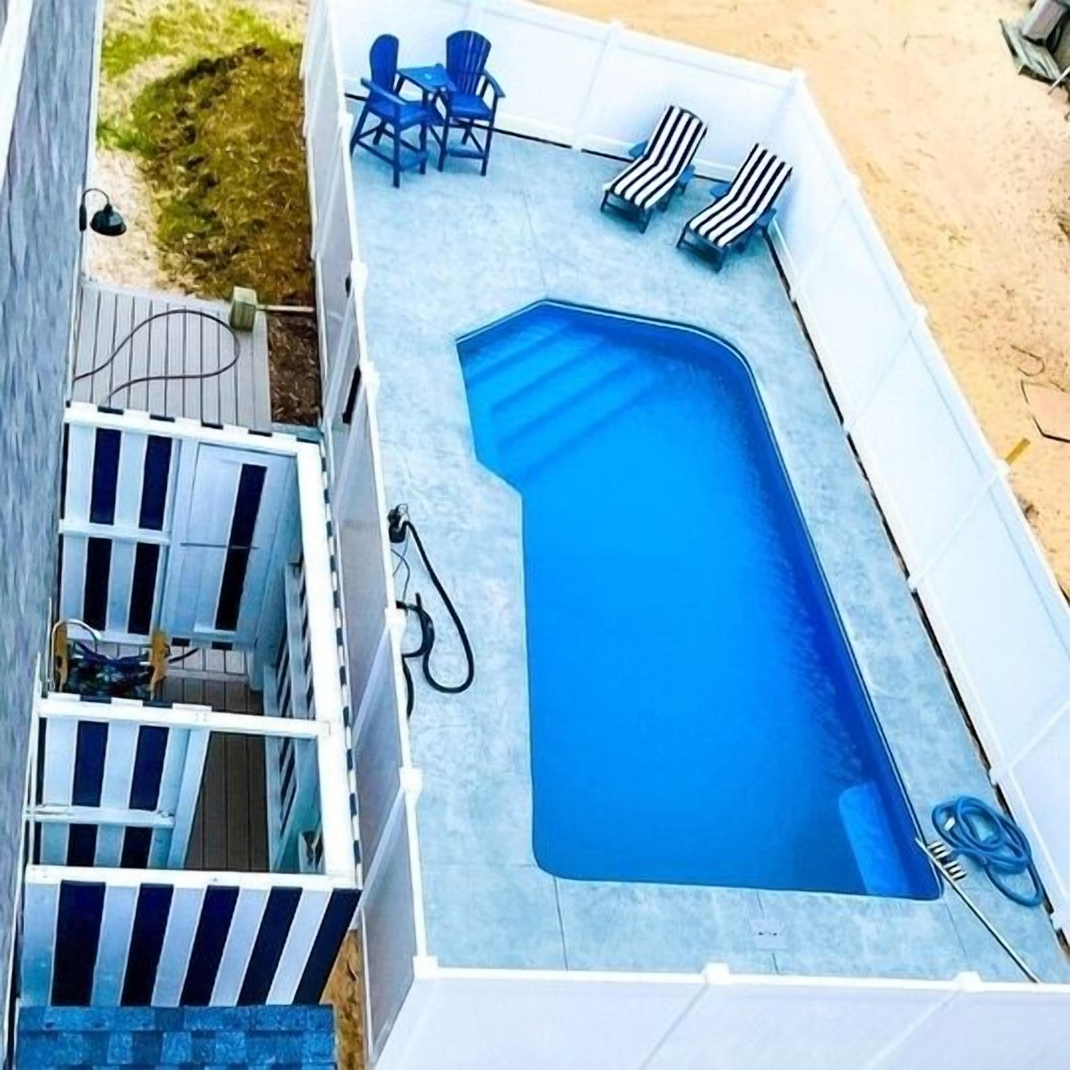 En overjordisk swimmingpool med liggestole og en terrassemiljø.