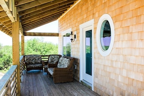 A covered porch with wicker furniture and a wooden deck. - 4X4 beach. Private Pool opens in May (Corolla)