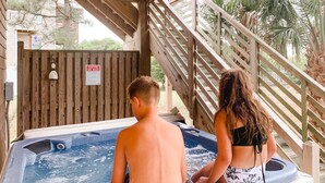 A wooden spa area with a hot tub, wooden stairs, and a caution sign. - 4X4 beach. Private Pool opens in May (Corolla)