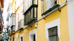 A narrow street with yellow and white buildings, balconies, and a cobblestone path.