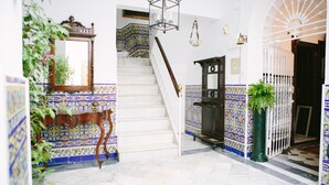 A staircase with a white railing, a wooden bench, and a green potted plant.