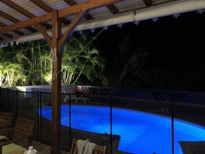 A swimming pool with a wooden deck and glass railing, surrounded by tropical plants. - House / Villa - SAINTE-LUCE (ST Luce)