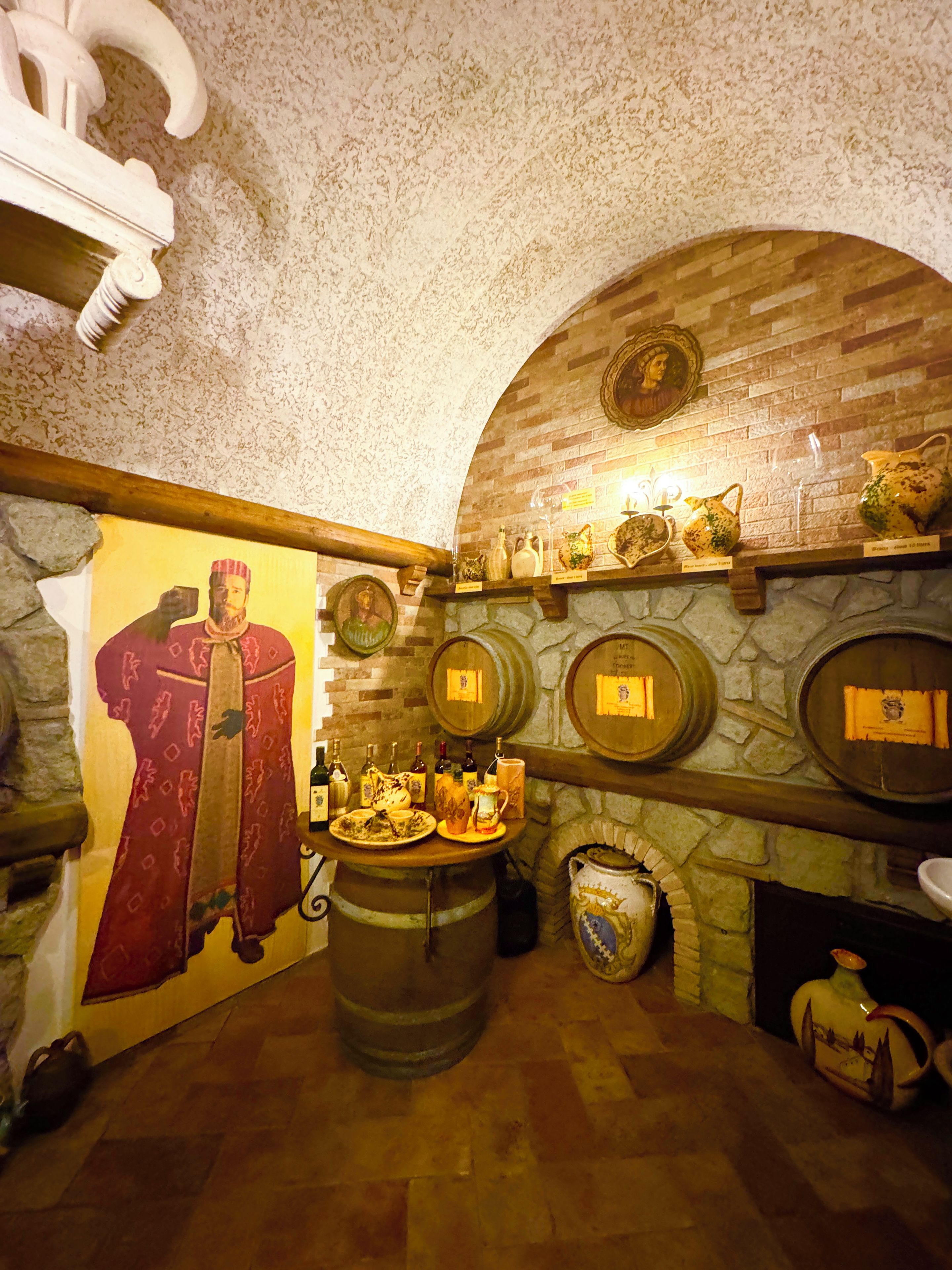 A room with a stone fireplace, wooden barrel, and a mural of a historical figure.