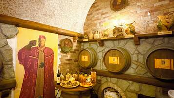 A room with a stone fireplace, wooden barrel, and a mural of a historical figure.