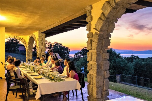 Una larga mesa de comedor lista para una comida, con vista al atardecer y al paisaje.
