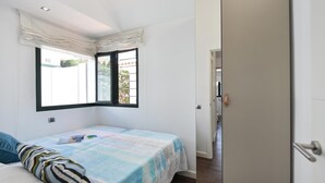 Een slaapkamer met een bed, een raam en een deur.