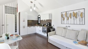 Een moderne keuken met witte kasten, een eethoek met een witte tafel en stoelen, en een woonkamer met een witte bank.