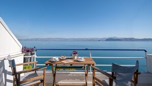 Ein Holztisch mit Meerblick, ein Geländer und ein Stuhl auf einem Balkon.