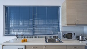 Eine moderne Küche mit Einbau-Mikrowelle, Spüle und einem Fenster mit Jalousien.