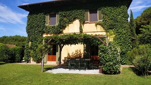 Uma casa de dois andares com paredes cobertas de hera e varanda de madeira.