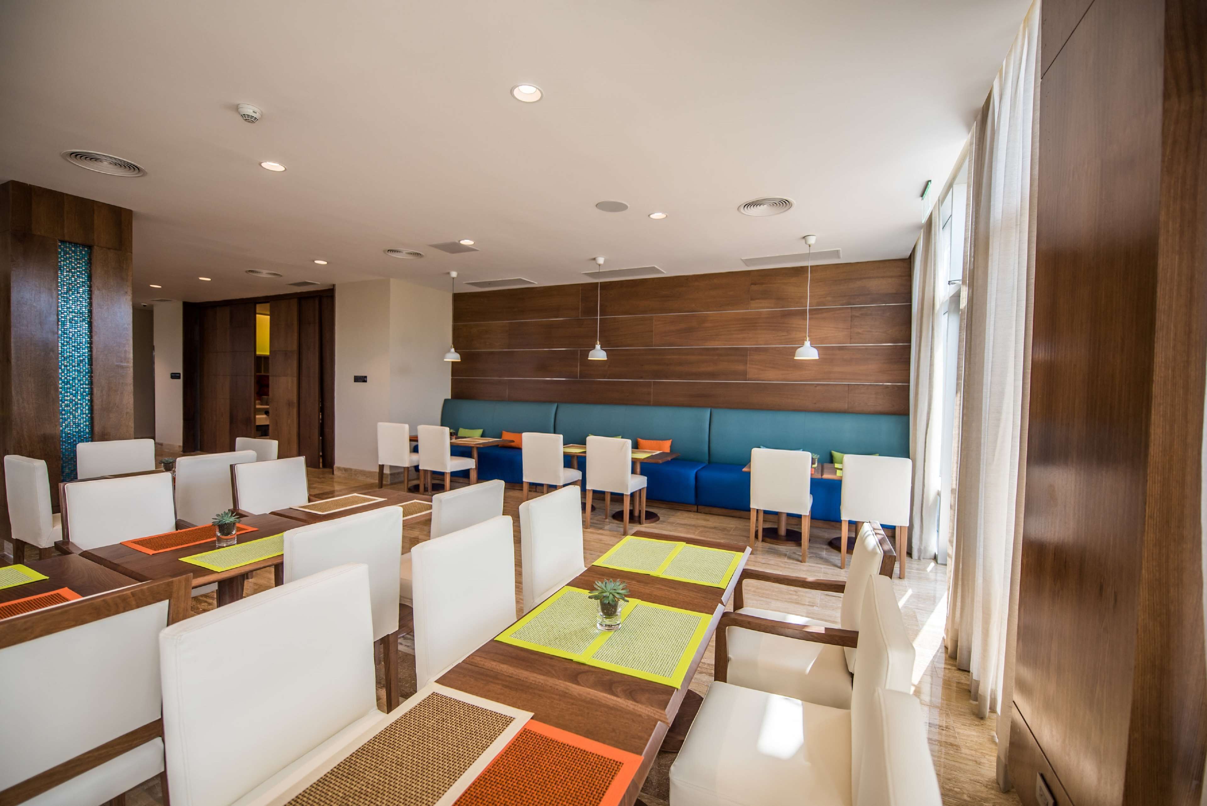 A modern dining area with wooden tables, white chairs, and blue seating.