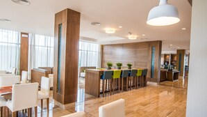 A modern hotel lobby with a dining area, a reception desk, and a bar. - Hampton by Hilton Santo Domingo Airport (Boca Chica)