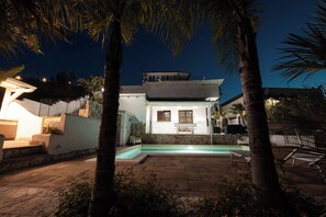 A modern house with a swimming pool, stone steps, and a balcony.