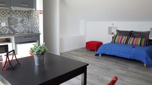 Een moderne slaapkamer met een bed, nachtkastje en een rode poef.