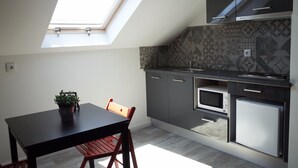 Een compacte keuken met dakraam, moderne apparatuur en een eethoek met tafel en stoelen.