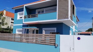 Een gebouw met twee verdiepingen, een blauwe gevel, een balkon en een hekwerk.