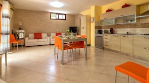 Cozinha moderna com área de refeições, com uma janela grande, uma televisão de tela plana e um micro-ondas.