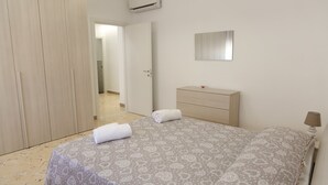 A bedroom with a bed, a wardrobe, a bedside table, and a mirror.