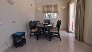 A dining area with a round table, four chairs, a small side table, and a window with curtains. - Beautiful Residential Villa on An Exclusive Private Complex, pool, roof terrace (Carvoeiro)
