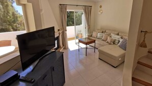 A living room with a TV, sofa, and a small table. - Beautiful Residential Villa on An Exclusive Private Complex, pool, roof terrace (Carvoeiro)