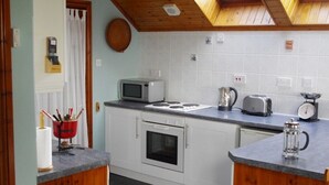 A compact kitchen with white cabinets, a microwave, a toaster, and a coffee maker.