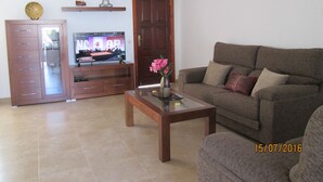 Una sala de estar con televisor, sofá, mesa de centro y aparador.