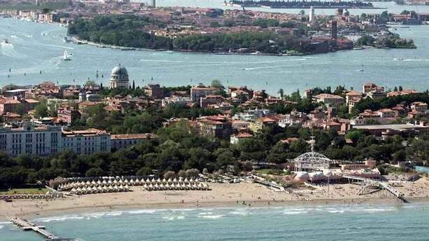A coastal cityscape with a prominent dome and a beach area with umbrellas.