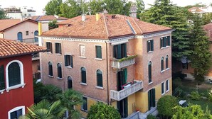 A multi-story building with a red-tiled roof, brick facade, and multiple balconies.