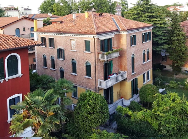 A multi-story building with a red-tiled roof, brick facade, and multiple balconies.