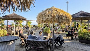 An outdoor seating area with thatched umbrellas and wooden furniture.
