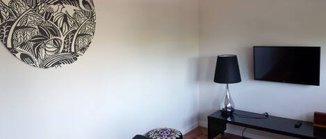 A living room with a round black and white wall art, a black lamp, a TV, and a black sofa.