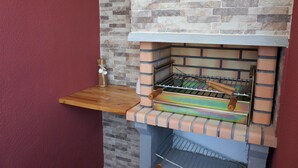 A brick oven with a wooden shelf and a metal rack. - Lisbon Beach Apartments 3. Beach 5 minutes, terrace, barbecue, pets welcome (Costa da Caparica)