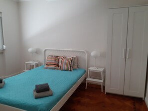 A bedroom with a bed, two bedside tables, a wardrobe, and a window.
