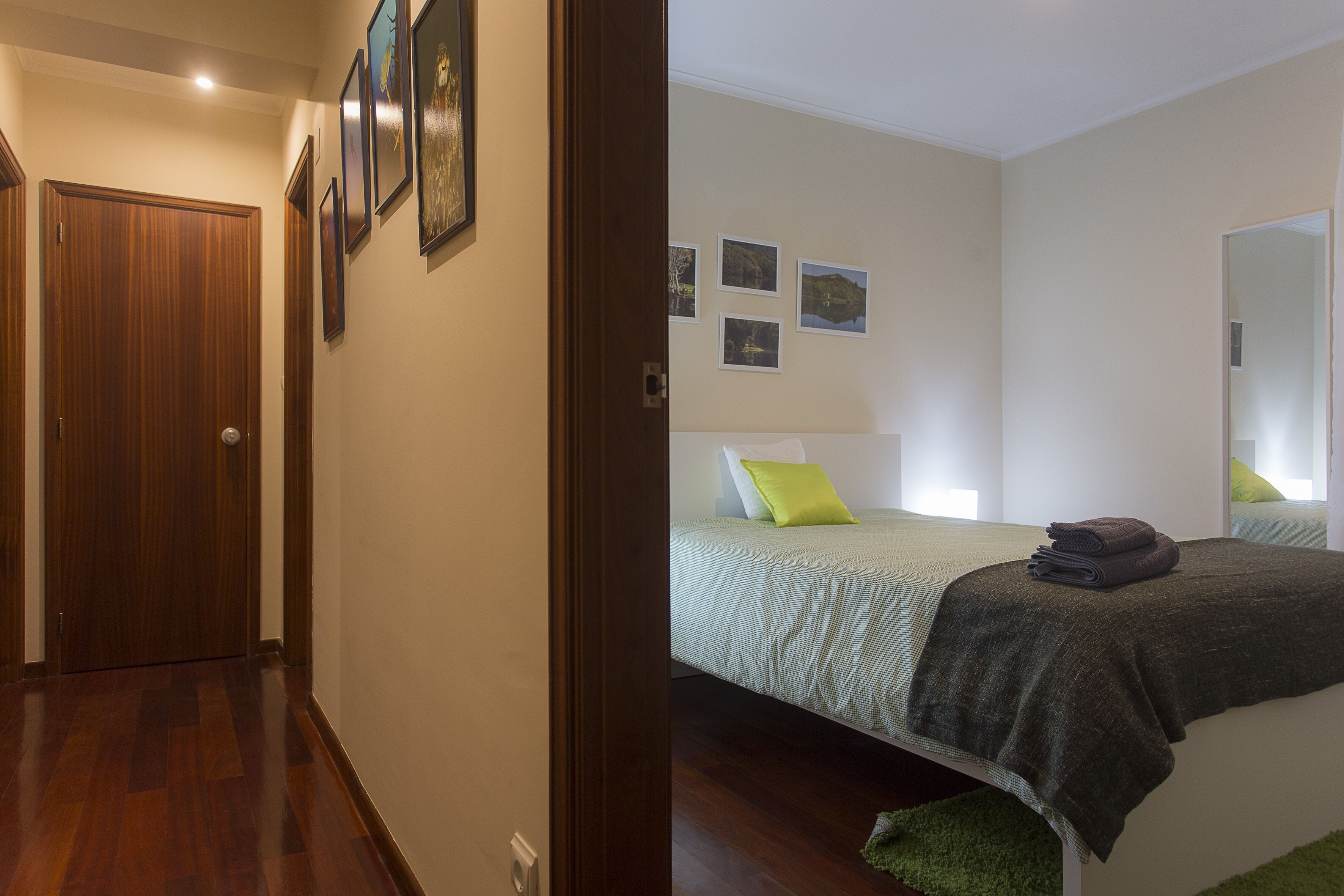 Une chambre à coucher avec un lit, des oreillers verts, une serviette pliée et un tapis vert.