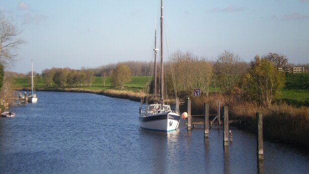 Une rivière paisible où un voilier est amarr é à un quai en bois.