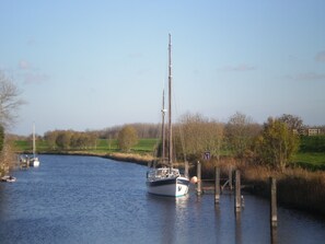 A calm river with a sailboat docked at a wooden pier.