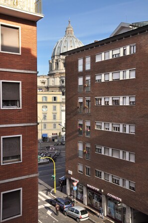 A street view with a prominent red brick building, a dome structure in the background, and a storefront with a sign. - Wonderful apartment in the center of Rome 100 meters from Vatican  (Roma)