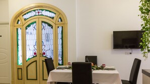 A dining area with a table set for two, a television mounted on the wall, and a stained glass door. - Wonderful apartment in the center of Rome 100 meters from Vatican  (Roma)