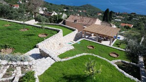 Una villa con muro de piedra, piscina y vista al mar.