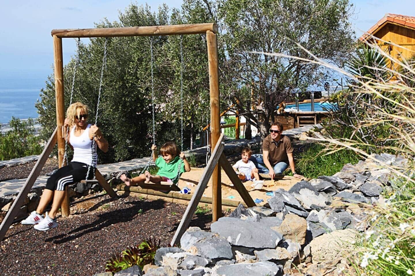 A playground with swings and a child sitting on the ground.