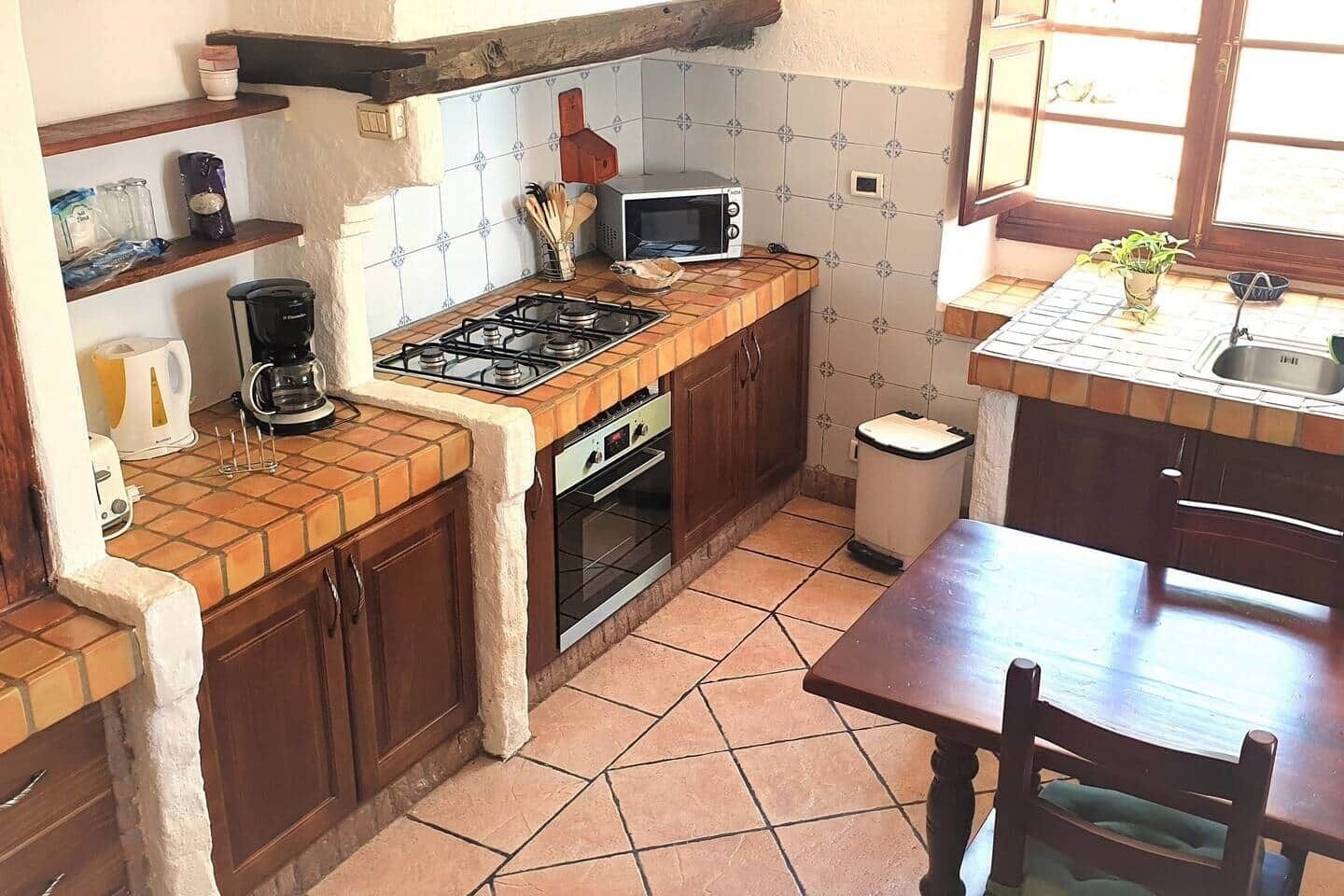 A compact kitchen with a gas stove, microwave, and a small trash bin.