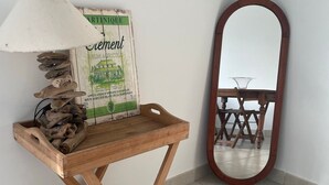 A wooden table with a lamp and a mirror, positioned against a white wall with a tiled floor.
