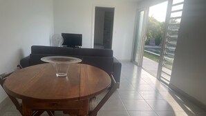 A modern living room with a wooden dining table, a sofa, and a TV.