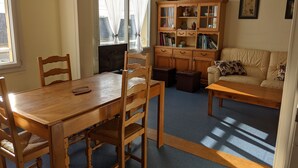 Un salón acogedor con una mesa de comedor de madera, sillas, un sofá y una estantería.