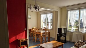 Una sala de estar con sofá, mesa de centro, mueble para televisor y comedor con mesa y sillas.