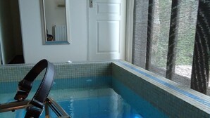 A small indoor pool with tiled edges, a candle, and a chair with a strap.