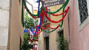 A narrow street with a restaurant sign, potted plants, and a cobblestone path.