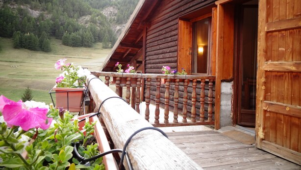 Een houten chalet met balkon met uitzicht op een bergachtig landschap.